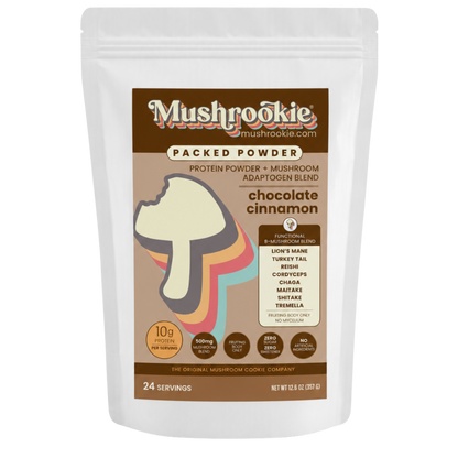 A white stand-up pouch of Mushrookie Packed Powder chocolate cinnamon mushroom powder and mushroom blend, featuring a brown label with a mushroom graphic and serving size 24.