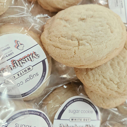 Several round sugar cookies in clear plastic bags with white circular labels reading 'Mushroom Cookie' and 'White Out'.